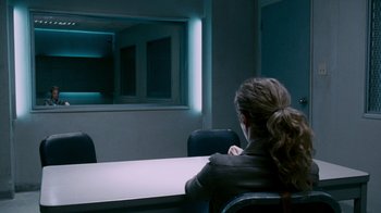 Movie still from “Saw IV” (2007), directed by Darren Lynn Bousman – A woman sitting at a table in front of a window; Wide shot, Over the shoulder angle