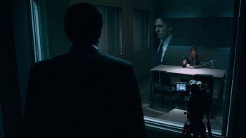 Movie still from “Saw IV” (2007), directed by Darren Lynn Bousman – A man in a suit and tie in front of a man in a suit and tie in front of a table; Medium shot, Over the shoulder angle