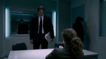 Movie still from “Saw IV” (2007), directed by Darren Lynn Bousman – A man in a suit and tie holding a newspaper; Medium shot, Over the shoulder angle