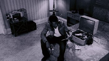 Movie still from “Saw IV” (2007), directed by Darren Lynn Bousman – A man sitting on the floor in a living room; Medium shot, High angle