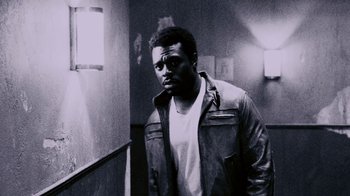 Movie still from “Saw IV” (2007), directed by Darren Lynn Bousman – A black and white photo of a man standing in a hallway; Medium shot, Low angle