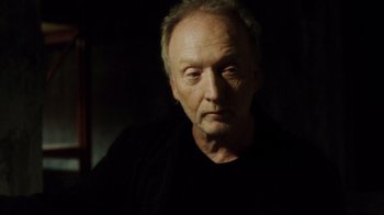 Movie still from “Saw IV” (2007), directed by Darren Lynn Bousman – An older man with a goatee is looking at the camera; Close Up shot, Low angle