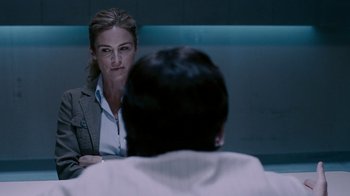 Movie still from “Saw IV” (2007), directed by Darren Lynn Bousman – A woman sitting in front of a man in front of a wall; Close Up shot, Over the shoulder angle