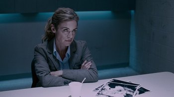 Movie still from “Saw IV” (2007), directed by Darren Lynn Bousman – A woman sitting at a table in front of an empty plate; Medium shot, Over the shoulder angle