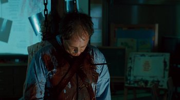 Movie still from “Saw IV” (2007), directed by Darren Lynn Bousman – A man in a blue shirt is tied up with chains; Close Up shot, Low angle