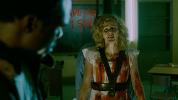 Movie still from “Saw IV” (2007), directed by Darren Lynn Bousman – A woman with blood all over her face is hanging from the ceiling; Medium shot, Over the shoulder angle