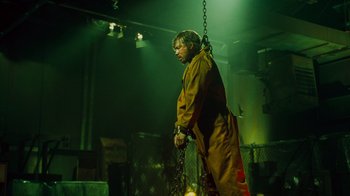 Movie still from “Saw IV” (2007), directed by Darren Lynn Bousman – A man chained up to a metal pole; Wide shot, Low angle