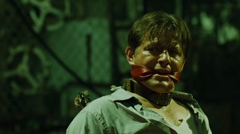 Movie still from “Saw IV” (2007), directed by Darren Lynn Bousman – A man with a red ribbon around his mouth; Close Up shot, Over the shoulder angle