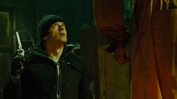 Movie still from “Saw IV” (2007), directed by Darren Lynn Bousman – A man wearing a black jacket and a hat looking up at a man wearing a black jacket; Medium shot, Low angle