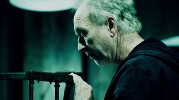 Movie still from “Saw IV” (2007), directed by Darren Lynn Bousman – An older man is holding a metal object; Close Up shot, Low angle