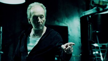 Movie still from “Saw IV” (2007), directed by Darren Lynn Bousman – An older man in a black jacket is pointing; Close Up shot, Over the shoulder angle