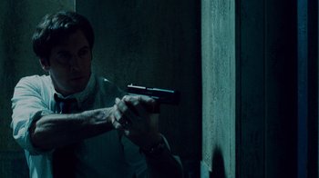 Movie still from “Saw IV” (2007), directed by Darren Lynn Bousman – A man holding a gun in front of a mirror; Medium shot, Low angle