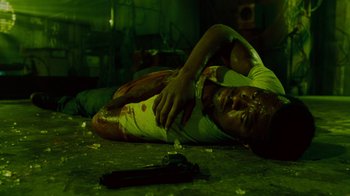 Movie still from “Saw IV” (2007), directed by Darren Lynn Bousman – A man laying on the ground with a gun in his hand; Medium shot, Overhead angle