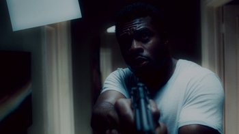 Movie still from “Saw IV” (2007), directed by Darren Lynn Bousman – A man is holding a gun in a room; Close Up shot, Low angle