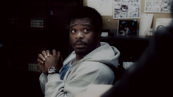 Movie still from “Saw IV” (2007), directed by Darren Lynn Bousman – A man sitting in a chair with his hands crossed; Close Up shot, Over the shoulder angle