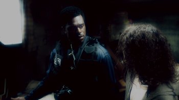 Movie still from “Saw IV” (2007), directed by Darren Lynn Bousman – A man in a police uniform is looking at a woman; Close Up shot, Over the shoulder angle