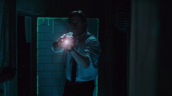 Movie still from “Saw V” (2008), directed by David Hackl – A man holding a flashlight in a dark room; Medium shot, Low angle