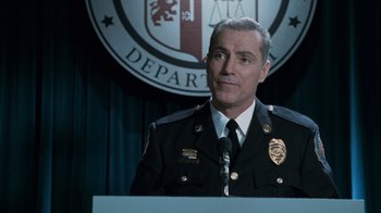 Movie still from “Saw V” (2008), directed by David Hackl – A man in a police uniform is standing at a podium; Close Up shot, Low angle