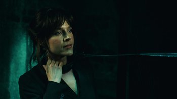 Movie still from “Saw V” (2008), directed by David Hackl – A man in a black shirt is holding his collar; Close Up shot, High angle