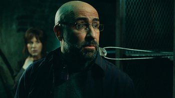 Movie still from “Saw V” (2008), directed by David Hackl – A bald man with glasses is looking at the camera; Close Up shot, Low angle