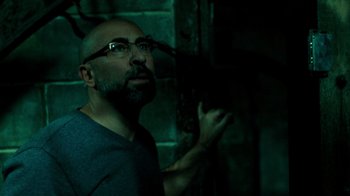 Movie still from “Saw V” (2008), directed by David Hackl – A man with a beard and glasses is looking up; Close Up shot, Low angle