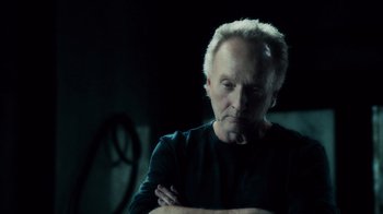 Movie still from “Saw V” (2008), directed by David Hackl – An older man is looking at the camera with his arms crossed; Close Up shot, Low angle