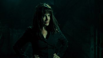 Movie still from “Saw V” (2008), directed by David Hackl – A woman standing in a dark room with her hands on her hips; Medium shot, Low angle