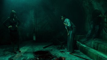 Movie still from “Saw V” (2008), directed by David Hackl – A man standing in a dark room with blood on the ground; Wide shot, High angle