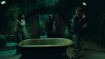 Movie still from “Saw V” (2008), directed by David Hackl – A group of people standing around a tub; Wide shot, High angle