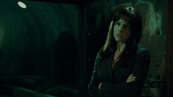 Movie still from “Saw V” (2008), directed by David Hackl – A woman standing in the dark with her arms crossed; Medium shot, Low angle