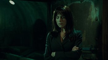 Movie still from “Saw V” (2008), directed by David Hackl – A woman standing with her arms crossed in a dark room; Medium shot, Low angle