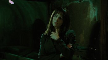 Movie still from “Saw V” (2008), directed by David Hackl – A woman standing in the dark with her arms folded around her chest; Close Up shot, Low angle