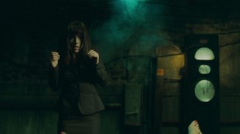 Movie still from “Saw V” (2008), directed by David Hackl – A woman standing in a dark room holding a umbrella; Medium shot, Over the shoulder angle