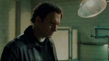 Movie still from “Saw V” (2008), directed by David Hackl – A man wearing a black leather jacket looking down; Close Up shot, Low angle