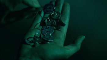 Movie still from “Saw V” (2008), directed by David Hackl – A hand holding a bunch of key chains in the dark; Extreme Close Up shot, Overhead angle