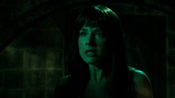 Movie still from “Saw V” (2008), directed by David Hackl – A woman with long dark brown hair and a green light; Close Up shot, Over the shoulder angle