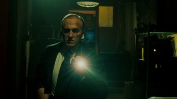 Movie still from “Saw V” (2008), directed by David Hackl – A man in a suit and tie holding a flashlight; Medium shot, Low angle