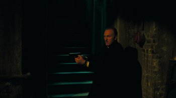 Movie still from “Saw V” (2008), directed by David Hackl – A man holding a gun while sitting on some steps; Medium shot, Low angle