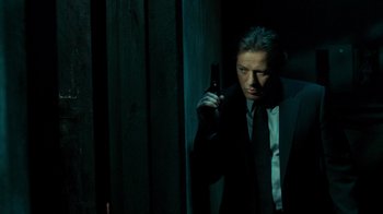 Movie still from “Saw V” (2008), directed by David Hackl – A man in a suit and tie holding a beer; Medium shot, Low angle