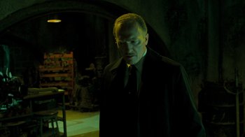 Movie still from “Saw V” (2008), directed by David Hackl – A man wearing a suit and tie standing in a dark room; Medium shot, Low angle