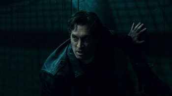 Movie still from “Saw V” (2008), directed by David Hackl – A man in a dark room looking at the camera; Close Up shot, Low angle