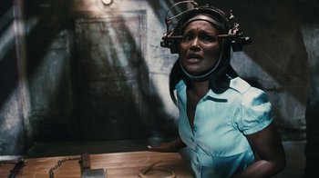 Movie still from “Saw VI” (2009), directed by Kevin Greutert – A woman sitting at a table wearing a hair dryer on top of her head; Close Up shot, Over the shoulder angle