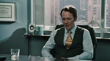 Movie still from “Saw VI” (2009), directed by Kevin Greutert – A man sitting at a desk in a room; Medium shot, Over the shoulder angle