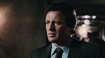 Movie still from “Saw VI” (2009), directed by Kevin Greutert – A person wearing a suit and tie; Close Up shot, Over the shoulder angle