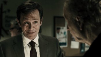 Movie still from “Saw VI” (2009), directed by Kevin Greutert – A man wearing a suit and tie talking to another man in a suit and tie; Close Up shot, Over the shoulder angle
