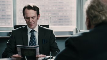 Movie still from “Saw VI” (2009), directed by Kevin Greutert – A man sitting at a table in front of a book; Close Up shot, Over the shoulder angle