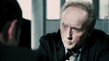 Movie still from “Saw VI” (2009), directed by Kevin Greutert – An older man is looking at the camera; Close Up shot, Over the shoulder angle