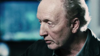 Movie still from “Saw VI” (2009), directed by Kevin Greutert – An older man with white hair looking to his left; Close Up shot, Over the shoulder angle