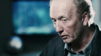 Movie still from “Saw VI” (2009), directed by Kevin Greutert – An older man is looking into the distance; Close Up shot, Over the shoulder angle