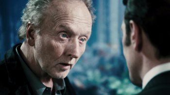 Movie still from “Saw VI” (2009), directed by Kevin Greutert – An older man looking at a younger man in a mirror; Close Up shot, Over the shoulder angle